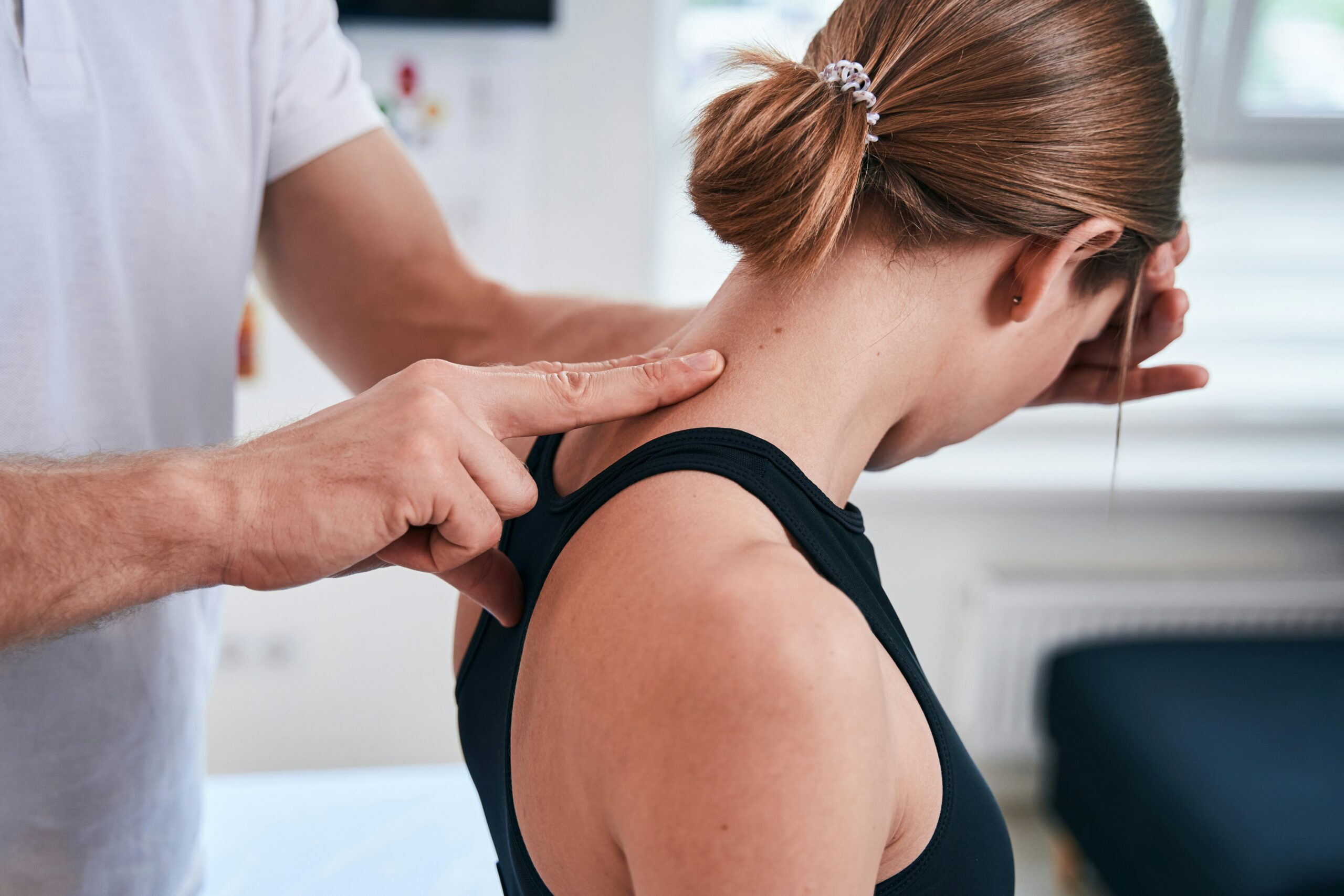 A chiropractor at Flexx Chiropractic in Columbus, MS, performing a cervical spine assessment on a patient to identify the root cause of persistent neck pain.